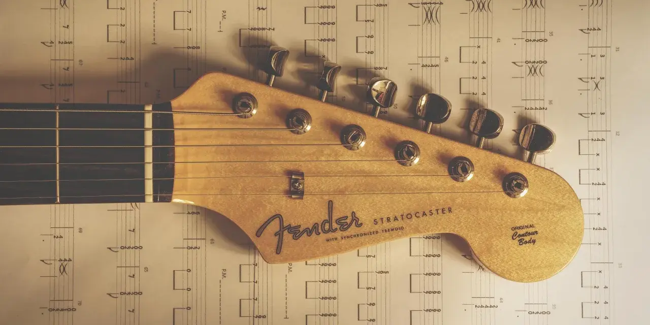 Głowa gitary Fender Stratocaster na tle nut. Idealne nuty na gitarę dla początkujących.
