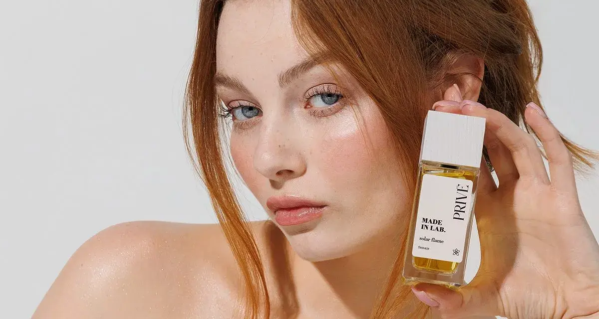 Ruda kobieta z niebieskimi oczami prezentuje perfumy "Made in Lab". Opinie o nich są zachęcające.