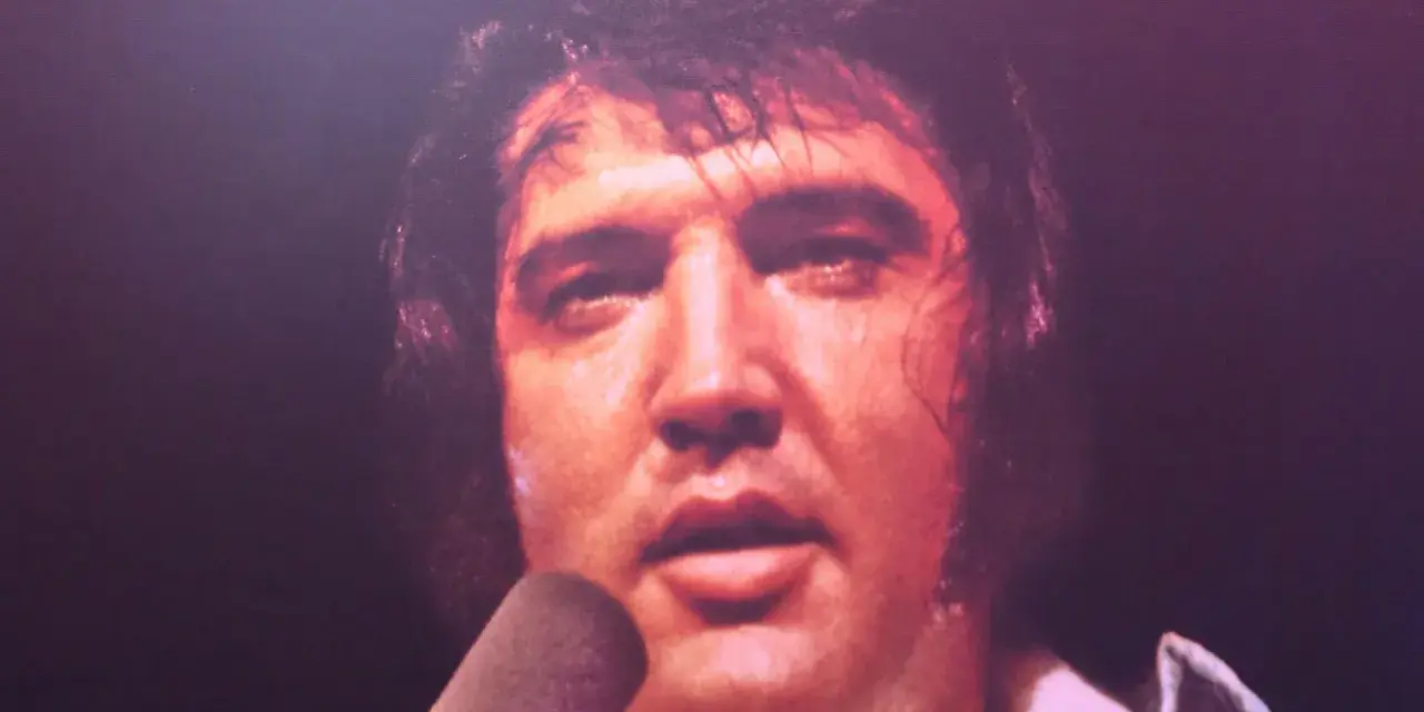 Elvis Presley, sichtlich erschöpft, singt in ein Mikrofon. Ein Moment, der an seinen elvis presley last concert erinnert.
