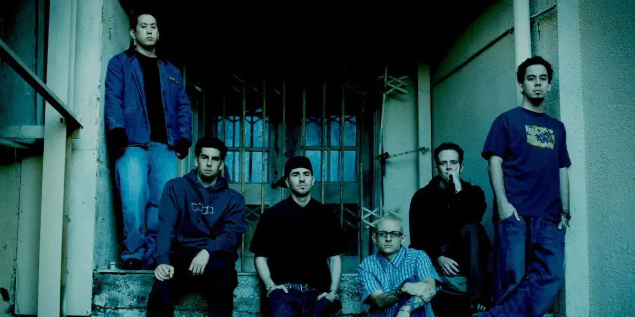 Sześciu członków zespołu Linkin Park, w tym Chester Bennington, pozuje na schodach.