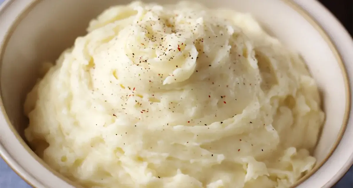 Un cremoso puré de patatas, espolvoreado con pimienta negra y roja, servido en un cuenco.