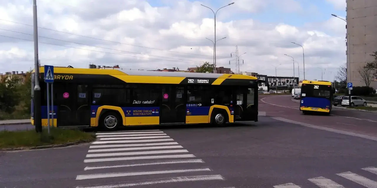 Autobus 262 z napisem "Dużo radości!" zbliża się do przejścia dla pieszych. Sprawdź autobus 136 rozkład jazdy.