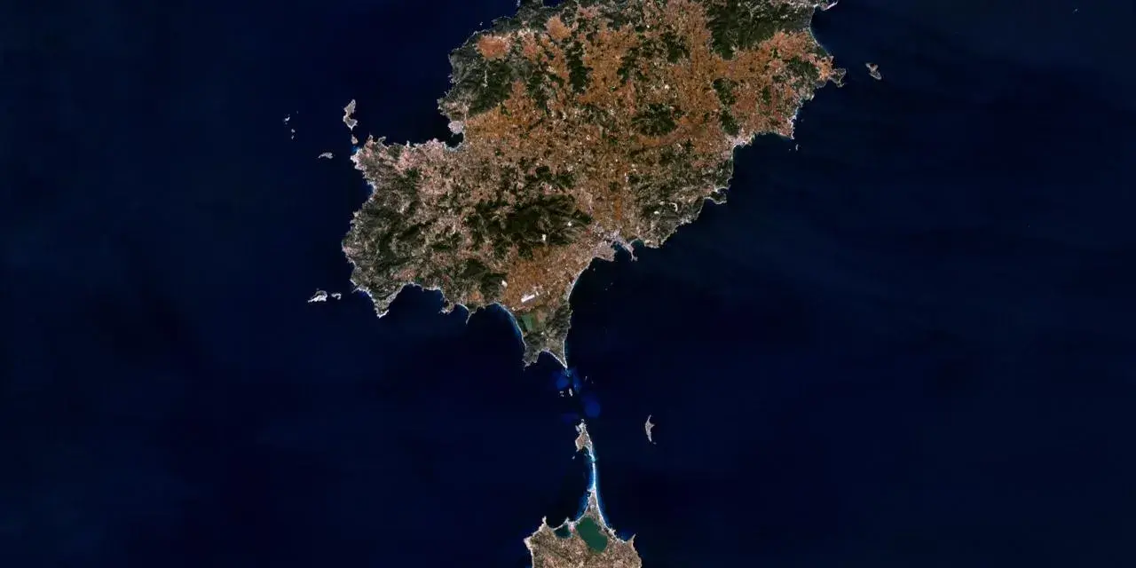 Widok z kosmosu na wyspy Ibiza i Formentera, gdzie jest Ibiza. Widać zielone wzgórza i zabudowania.