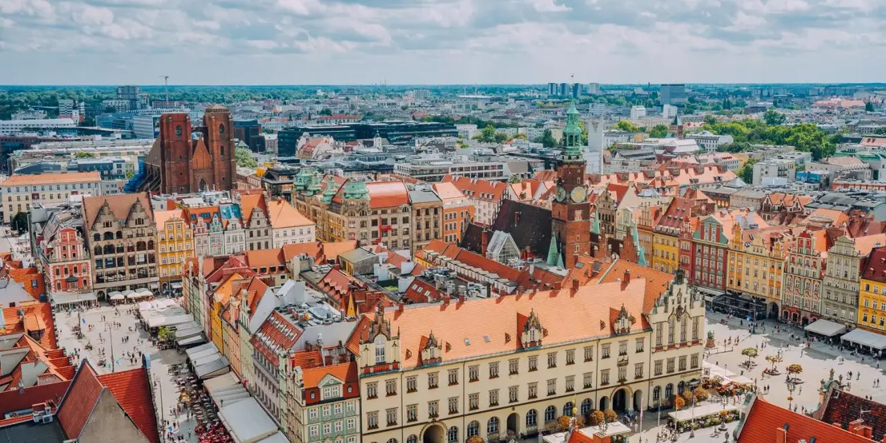 Wrocław słynie z kolorowych kamienic na Rynku i wież kościelnych. Widok z lotu ptaka na tętniące życiem miasto.