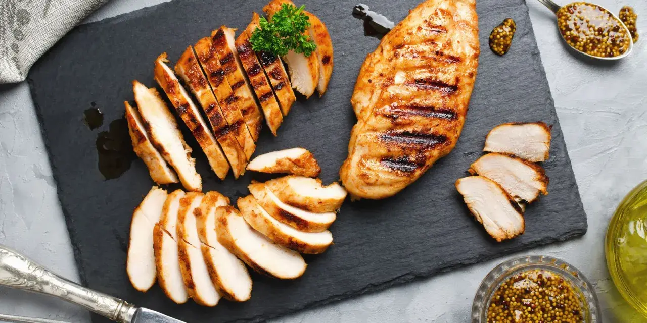 Deliziosa tagliata di pollo grigliata, servita su ardesia con senape e prezzemolo.