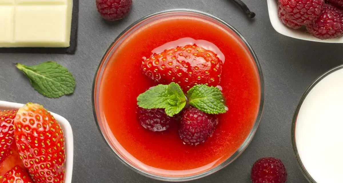 Delizioso dessert con coulis di fragole, fragole fresche, lamponi, menta, cioccolato bianco e un baccello di vaniglia.