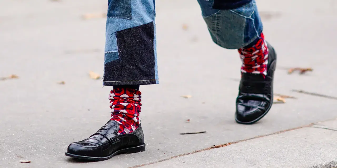 Pantaloni patchwork e scarpe eleganti con calzini rossi a fantasia, un look audace per sfidare le scarpe senza calze in inverno.