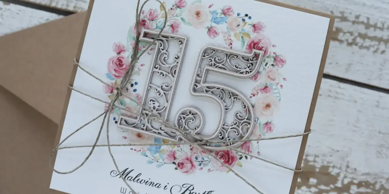 Elegancka kartka z napisem "15 rocznica ślubu" i imionami Malwina i Bartłomiej, ozdobiona kwiatowym wiankiem i sznurkiem.