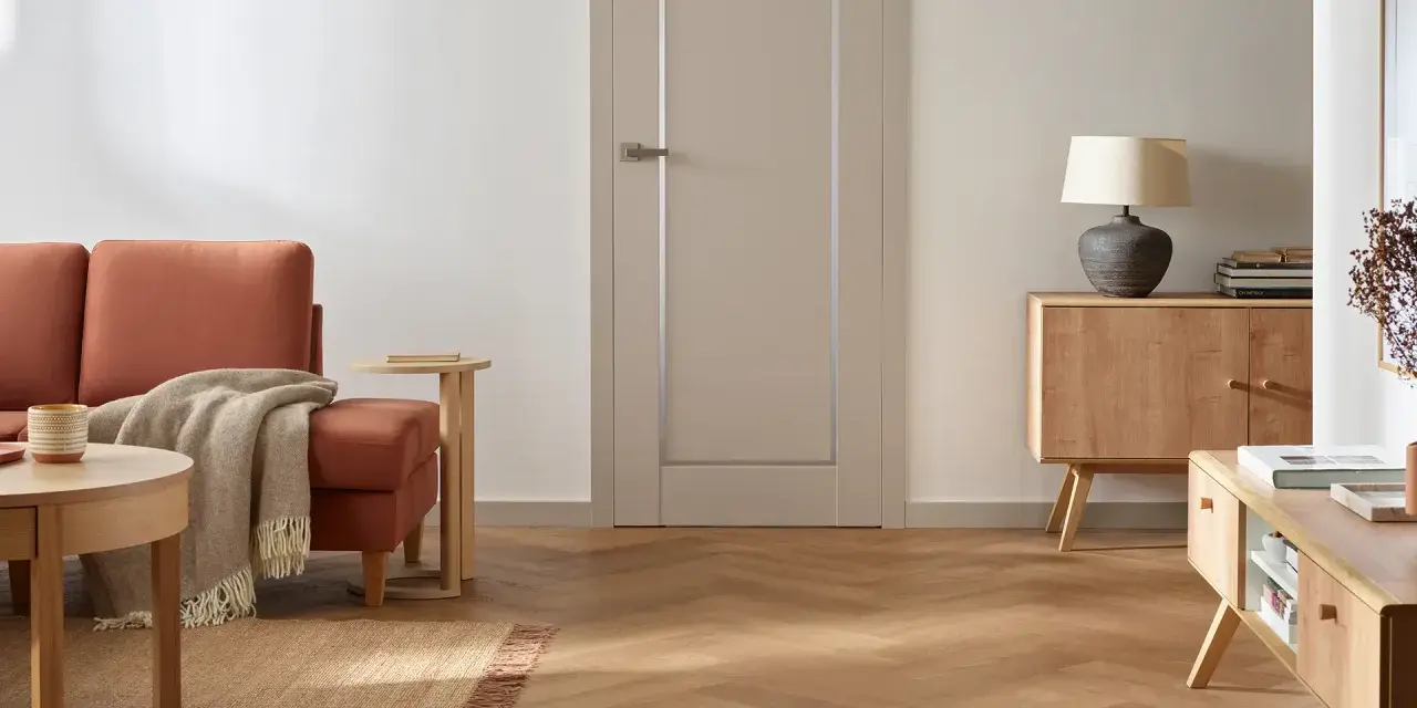 Nowoczesne wykończenie drzwi wewnętrznych w stonowanym kolorze, idealnie komponuje się z drewnianą podłogą i meblami.