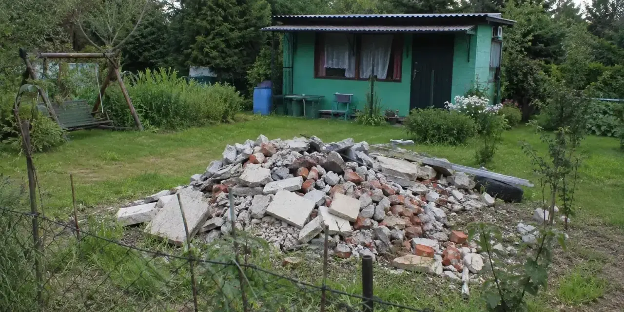 Kupa gruzu na działce ROD. Czy komornik może zająć działkę ROD? W tle zielona altanka, huśtawka i drzewa.