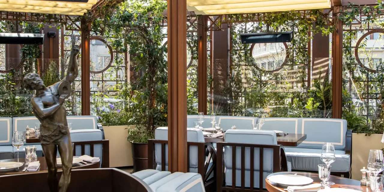 Terrazza lussuosa con statue e piante, tavoli apparecchiati per un'esperienza culinaria al **Wilde Milano**.
