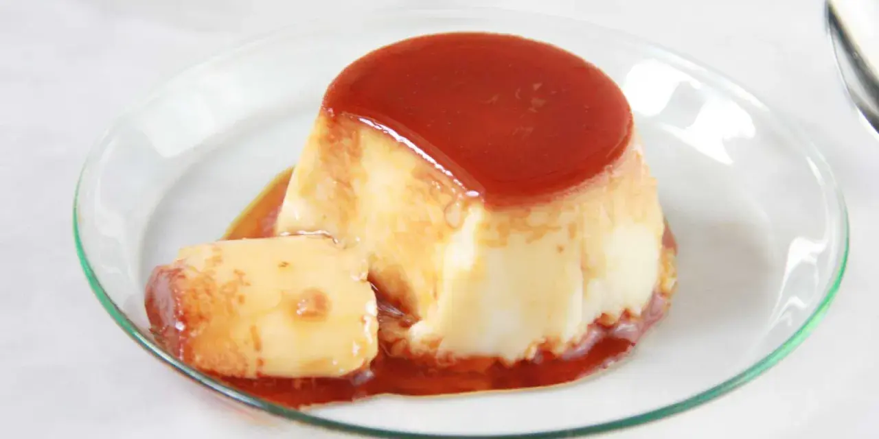 Delicioso flan de huevo en flanera con tapa, bañado en caramelo líquido y servido en un plato de cristal.