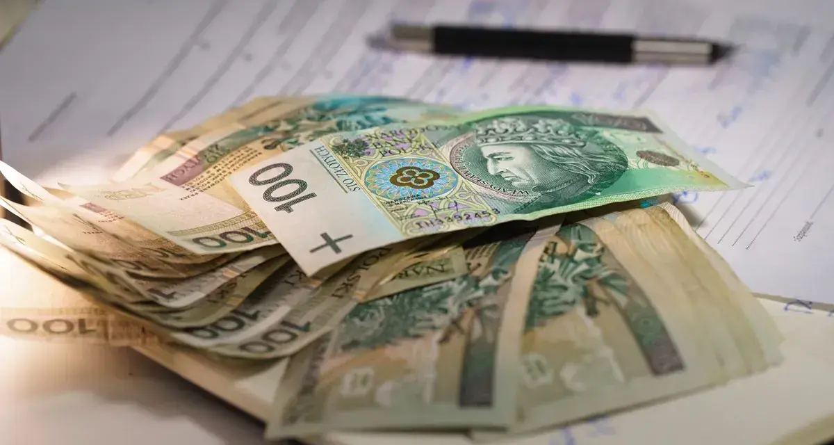 Stos banknotów 100 zł na dokumentach. Czy to wystarczy na najniższą emeryturę?
