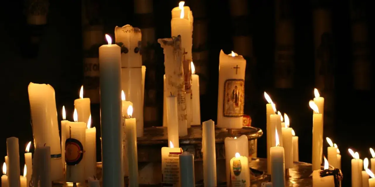 Viele Kerzen brennen in der Dunkelheit, einige mit Bildern und Kreuzen verziert. Ein stimmungsvolles Bild, das an Maria Lichtmess erinnert.