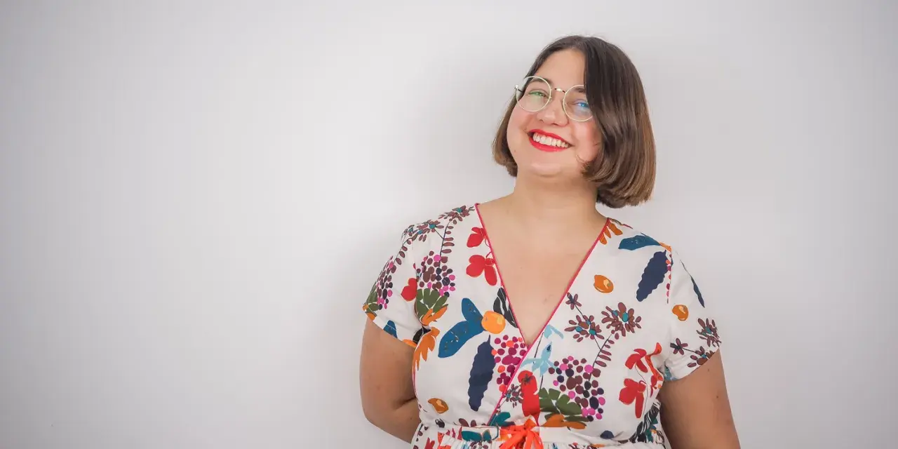 Une femme souriante porte une robe d'été colorée, un modèle inspiré d'un patron gratuit de robe Charlotte.