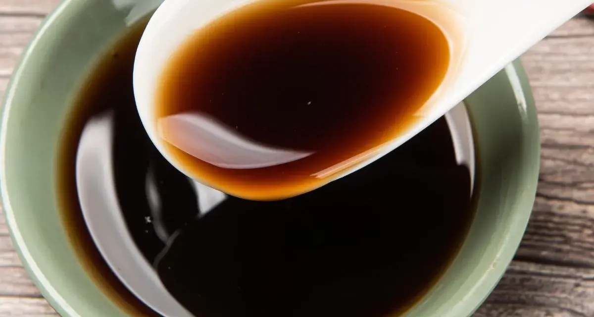 Łyżka z ciemnym, błyszczącym płynem, idealnym jako ocet balsamiczny do mięsa.