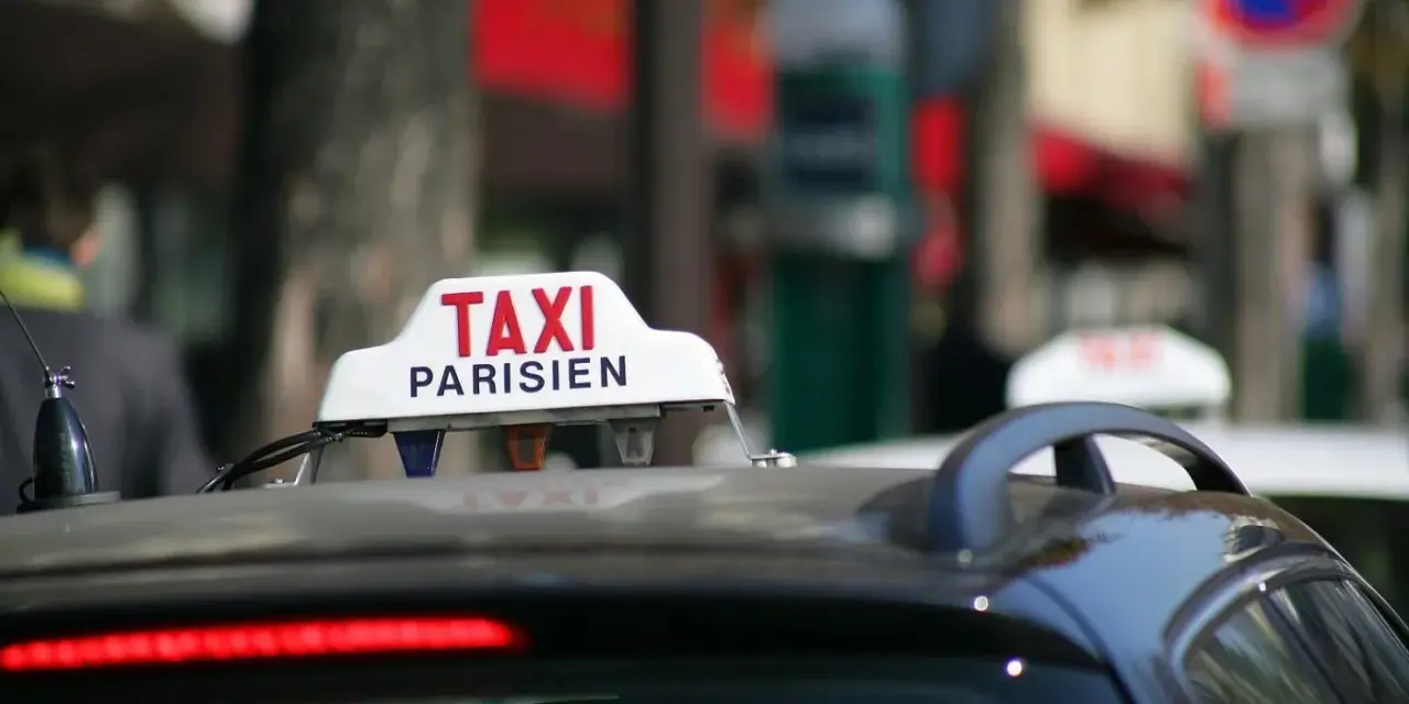 Ein Taxi in Frankreich, mit der Aufschrift "TAXI PARISIEN", wartet auf Fahrgäste.