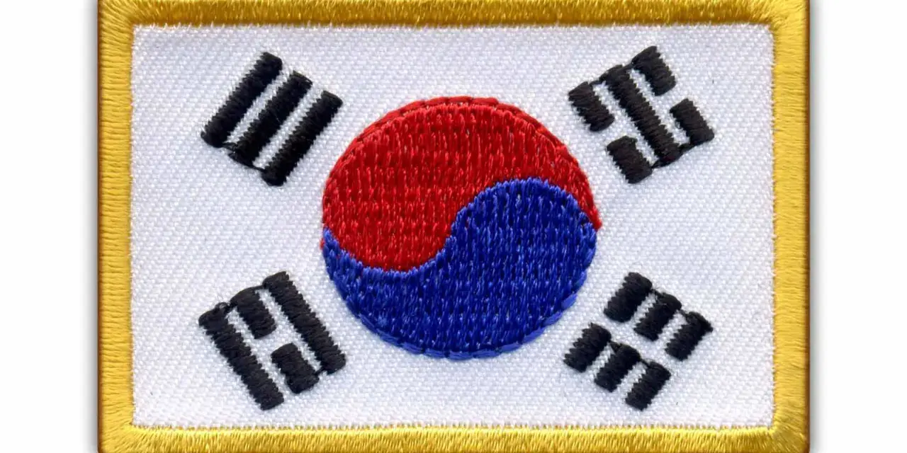Naszywka z flagą Korei Południowej. Białe tło, czerwono-niebieski symbol yin-yang i czarne trygramy.