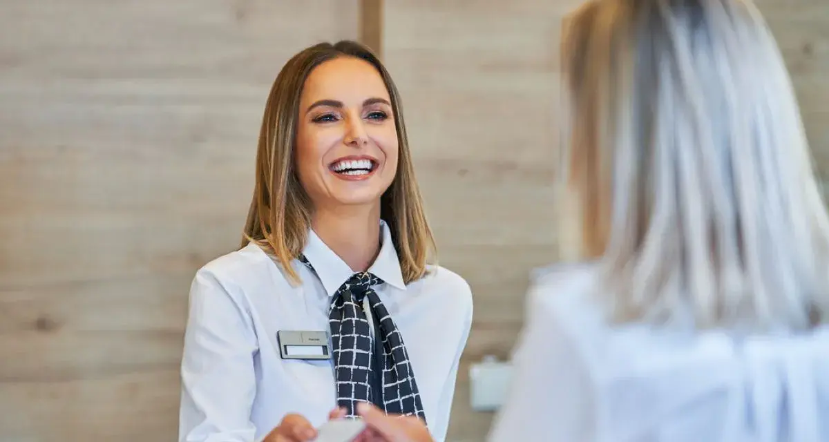 Una sorridente hostess di terra consegna una tessera a un cliente.