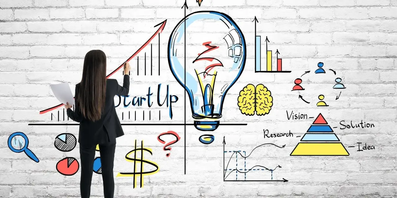 Mujer dibuja un gráfico de crecimiento y una bombilla, simbolizando cómo capitalizar el paro con una idea de startup.
