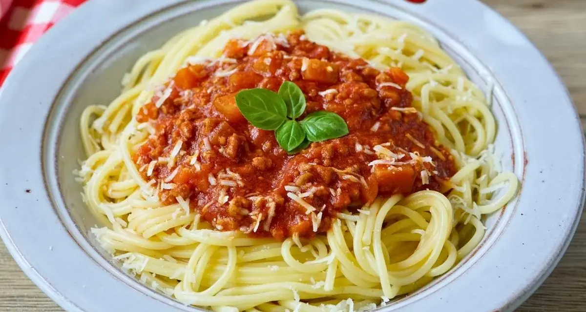 Teller mit Spaghetti Bolognese, bestreut mit Parmesan und garniert mit Basilikum. Perfekt für schnelle Bolognese für Kinder.