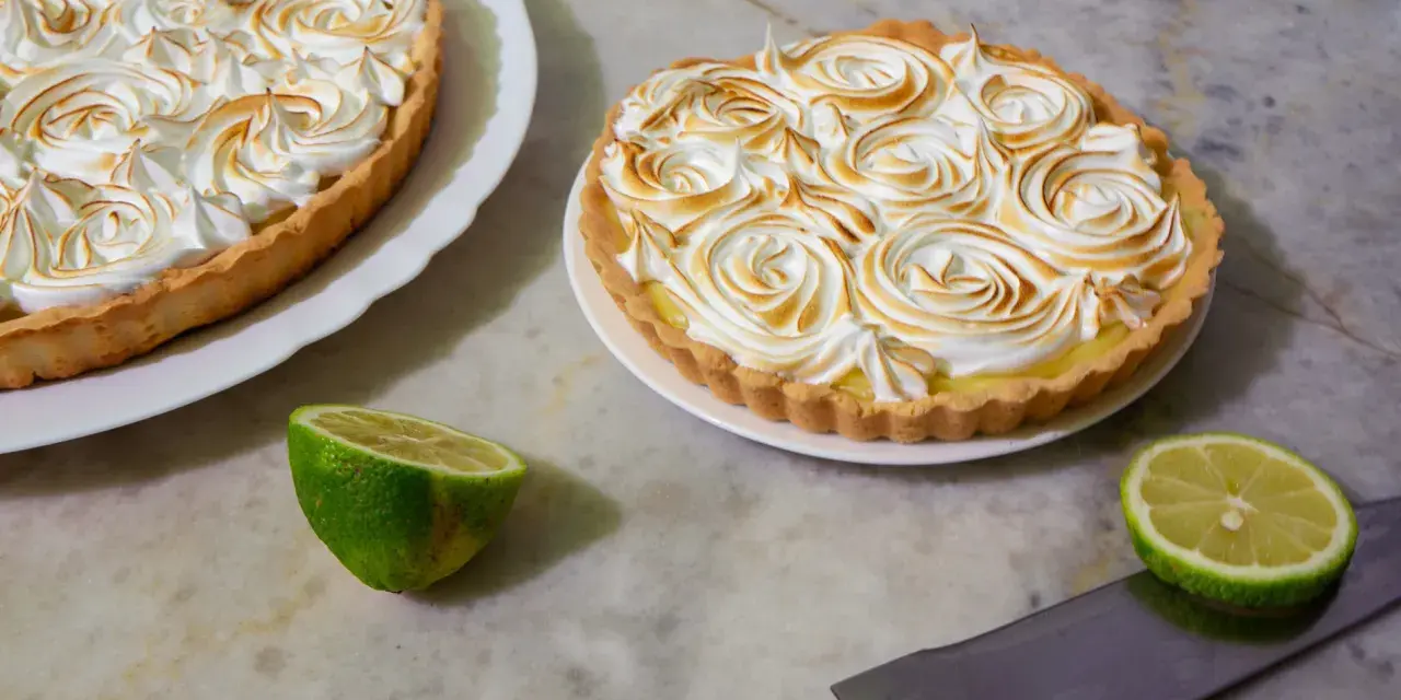 Dos deliciosas tartas de limón con merengue tostado, listas para ser cortadas.
