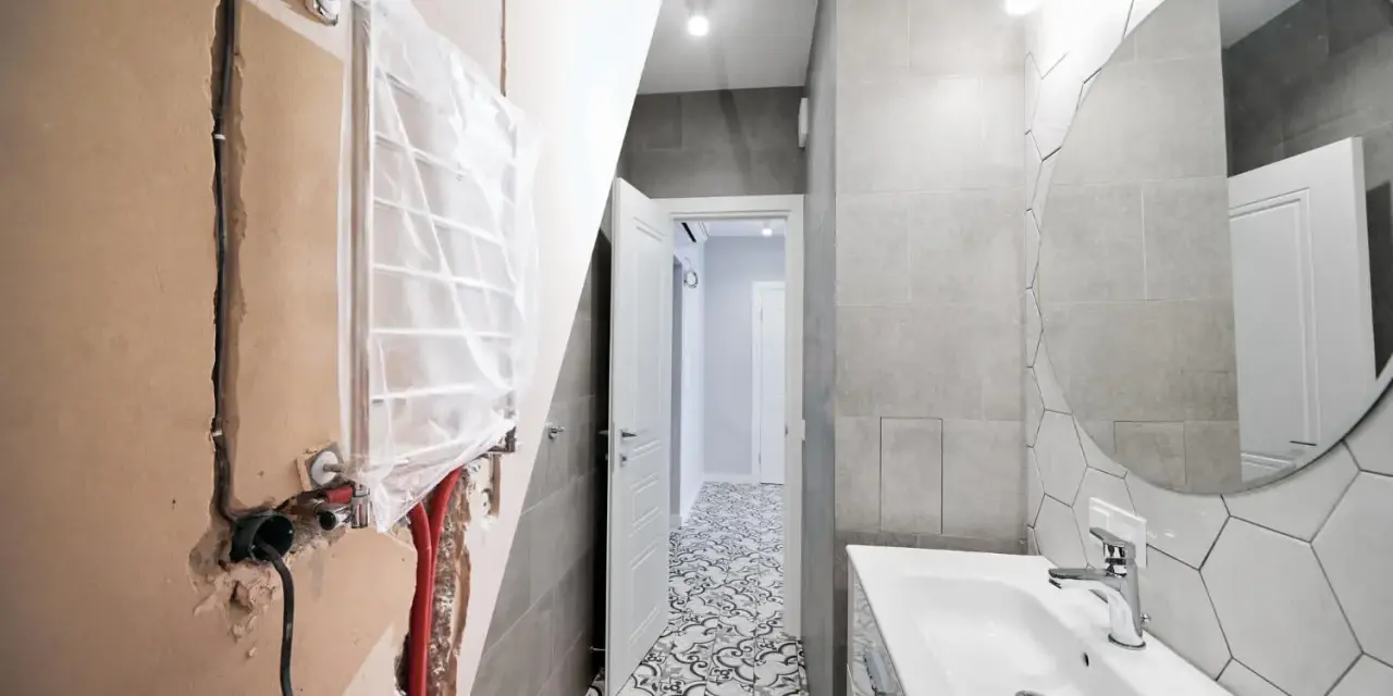 Bagno in ristrutturazione con impianto idraulico a vista, pronto per la detrazione 65. Pavimento decorato e lavabo moderno.