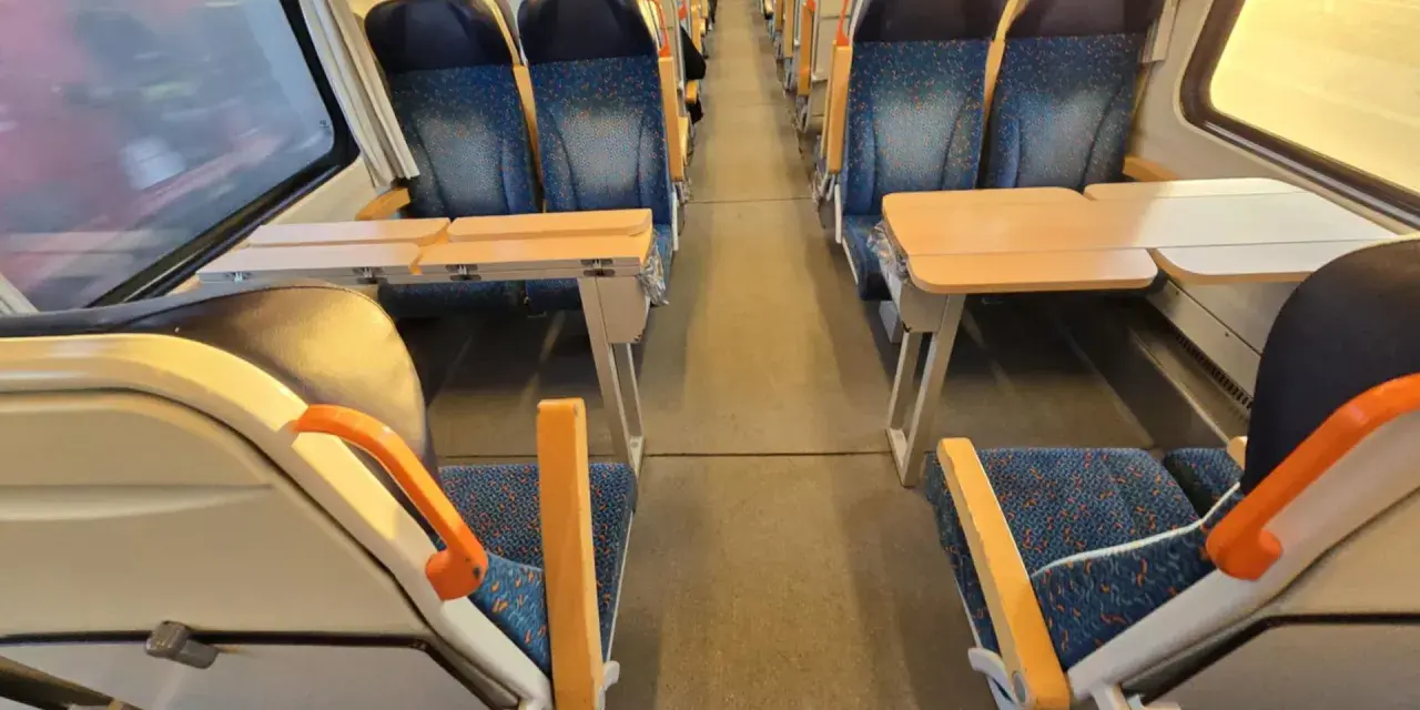 Pociąg do Pragi. Puste siedzenia z niebieskimi obiciami i stolikami czekają na pasażerów.