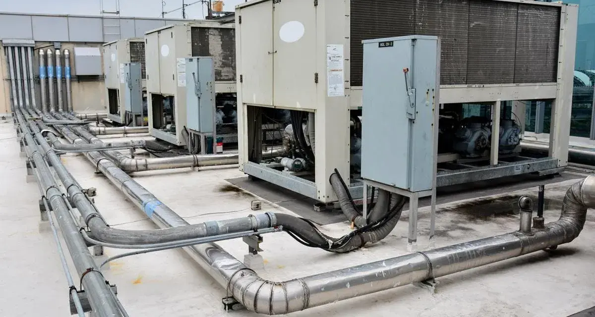 Unidades de aire acondicionado industriales en una azotea, con tuberías de ventilación y aire acondicionado (HVAC) conectadas.