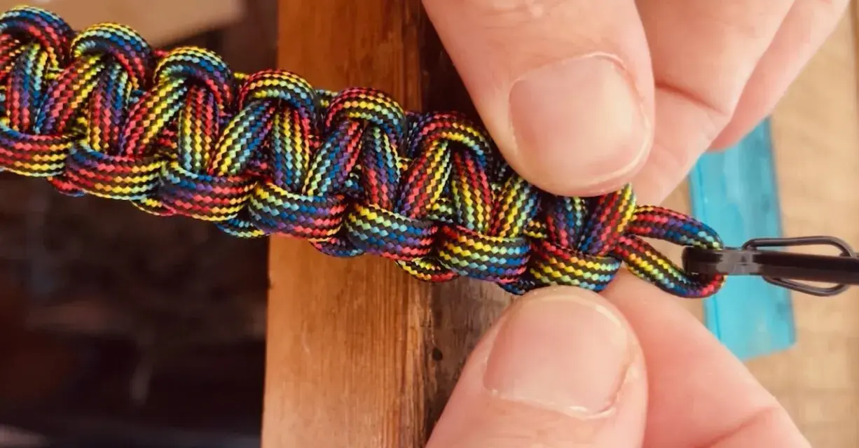 Mani che creano nodi per braccialetti elastici color arcobaleno, un'arte che unisce creatività e praticità.