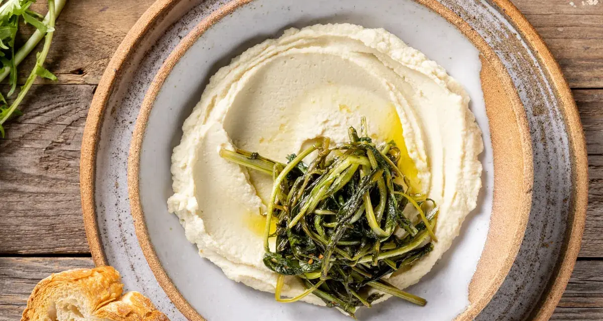 Crema di fave e cicoria saltata, servita su un piatto rustico con pane croccante.