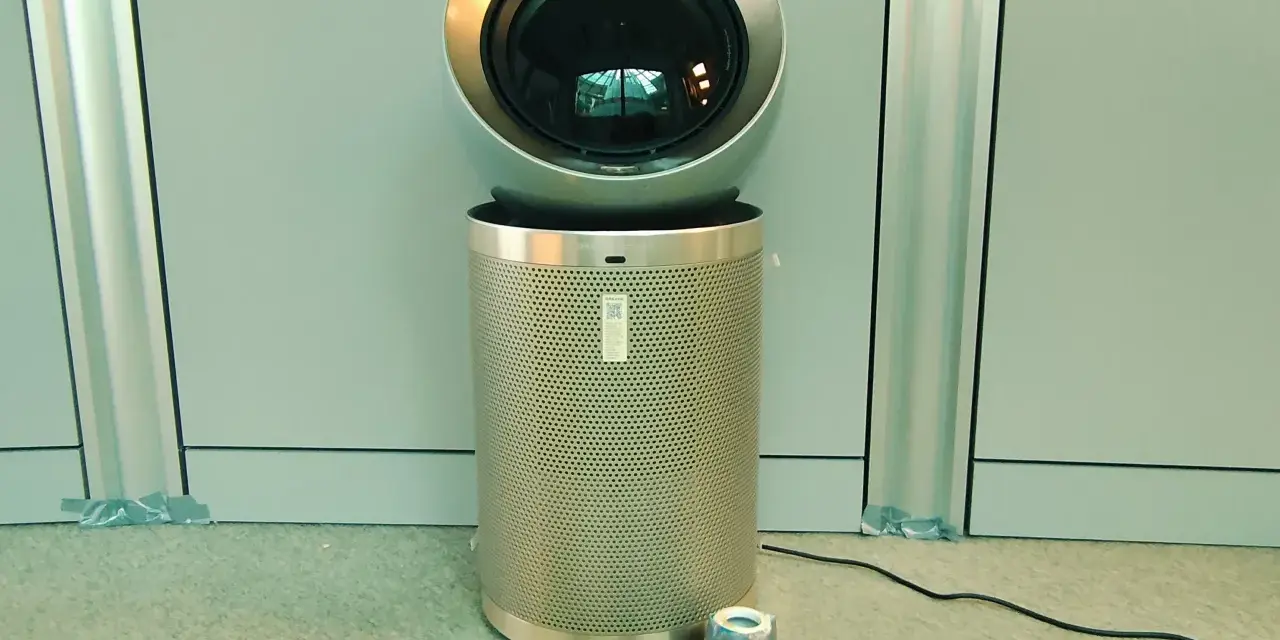 Nowoczesne oczyszczarki powietrza i sprzęt pomiarowy. Urządzenie z okrągłą górą i perforowanym cylindrem, obok taśma miernicza, miernik i inne akcesoria.