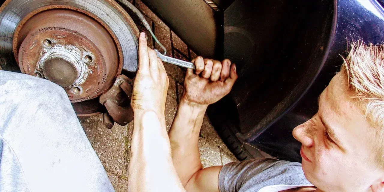 Ragazzo con mani sporche lavora sul freno, forse per un cuscinetto ruota rotto sintomi.