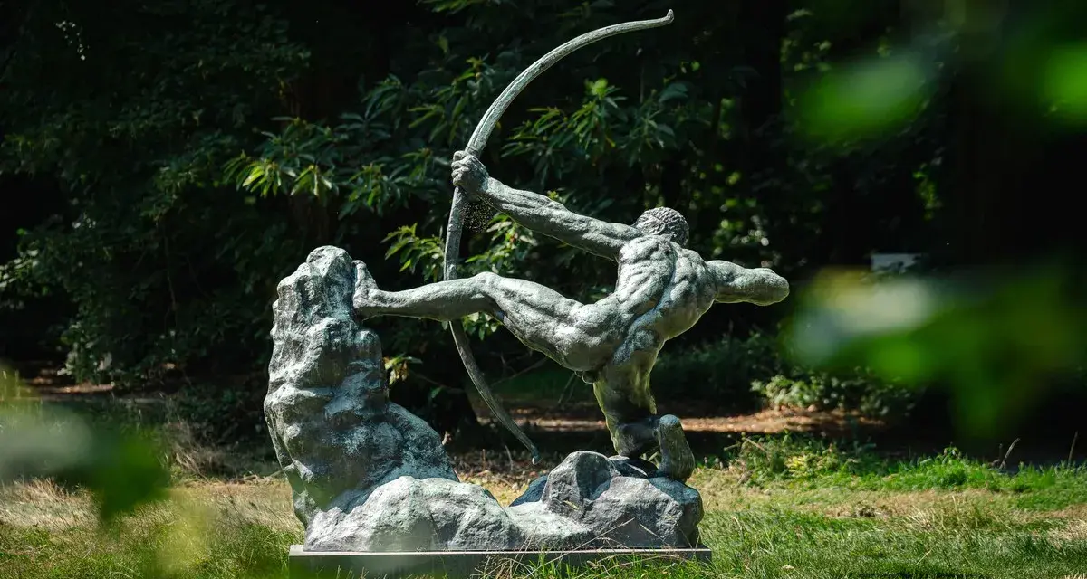La sculpture de l'archer, une œuvre d'Antoine Bourdelle, se dresse fièrement dans un jardin verdoyant, capturant l'instant d'une tension parfaite.
