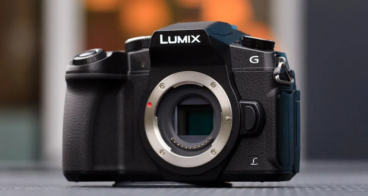 Czarny aparat Lumix G z widocznym mocowaniem obiektywu i migawką elektroniczną.