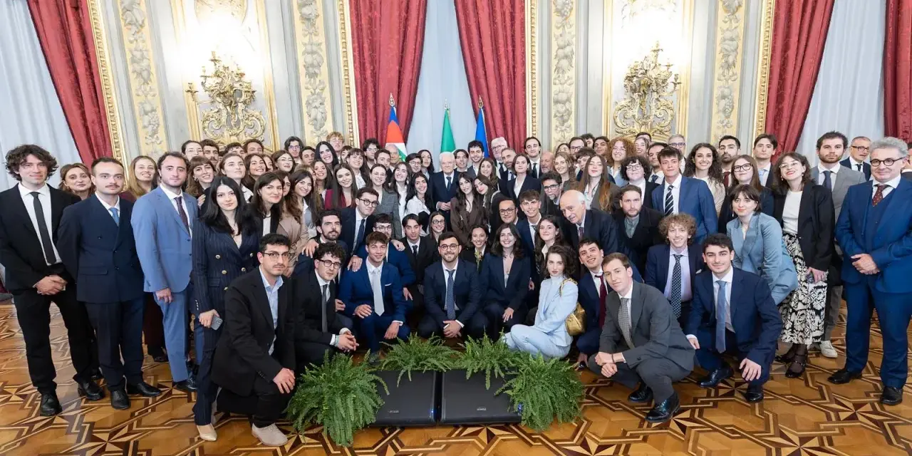 Un folto gruppo di giovani studenti posa per una foto di gruppo, forse dopo un evento alla scuola di giornalismo Roma.