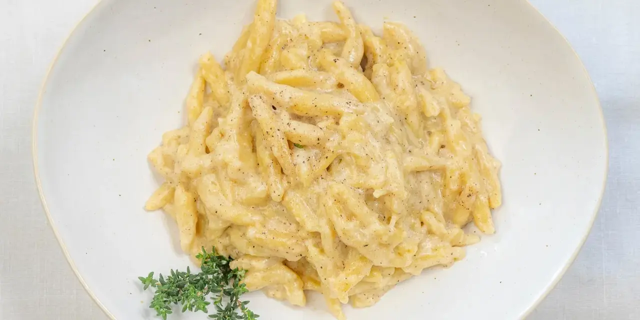 Ravioles val varaita, pasta fresca condita con una cremosa salsa al formaggio e pepe nero, guarnita con timo fresco.