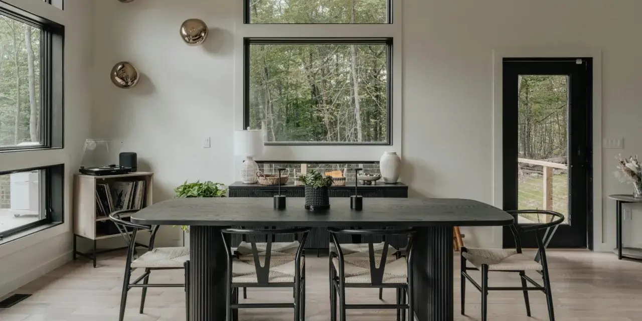 Elegante mesa negra y sillas de diseño para una perfecta decoracion comedores modernos. Ventanales con vistas al bosque.