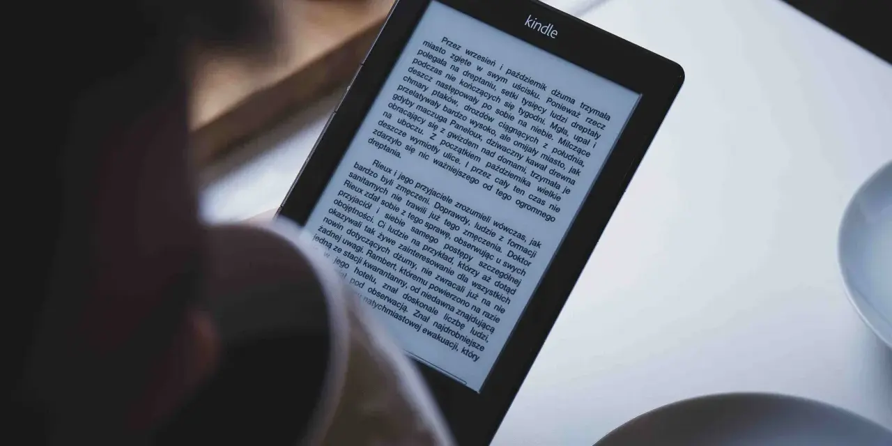 Osoba czyta książkę w formacie kindle. Na ekranie widoczny jest tekst powieści.