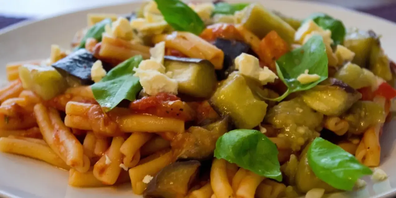 Pyszne danie z makaronem, bakłażanem i pomidorami, posypane serem i bazylią. Idealne na Pasta alla Norma przepis.