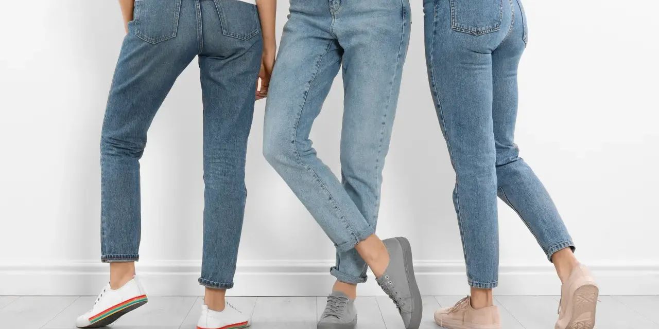 Trzy kobiety w jeansach i sneakersach. Dowiedz się, jak rozciągnąć jeansy, by były idealnie dopasowane.