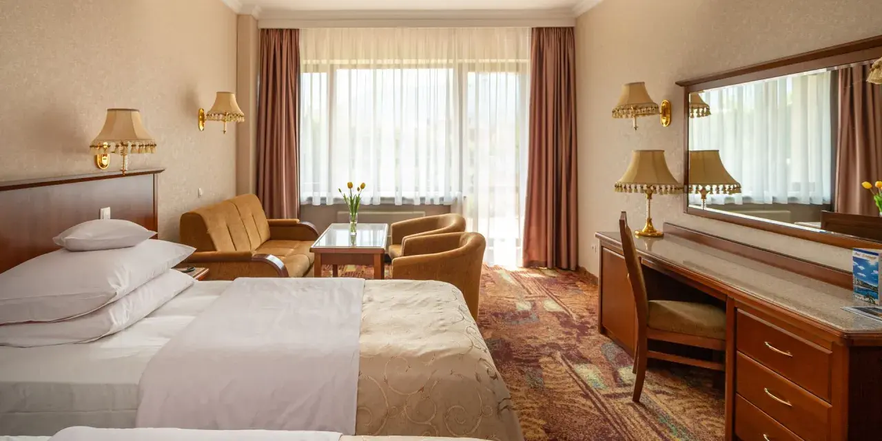 Pokój w Hotelu Gołębiewski Karpacz. Sprawdź cennik i zarezerwuj pobyt w tym przytulnym wnętrzu z dwoma łóżkami, kanapą i biurkiem.