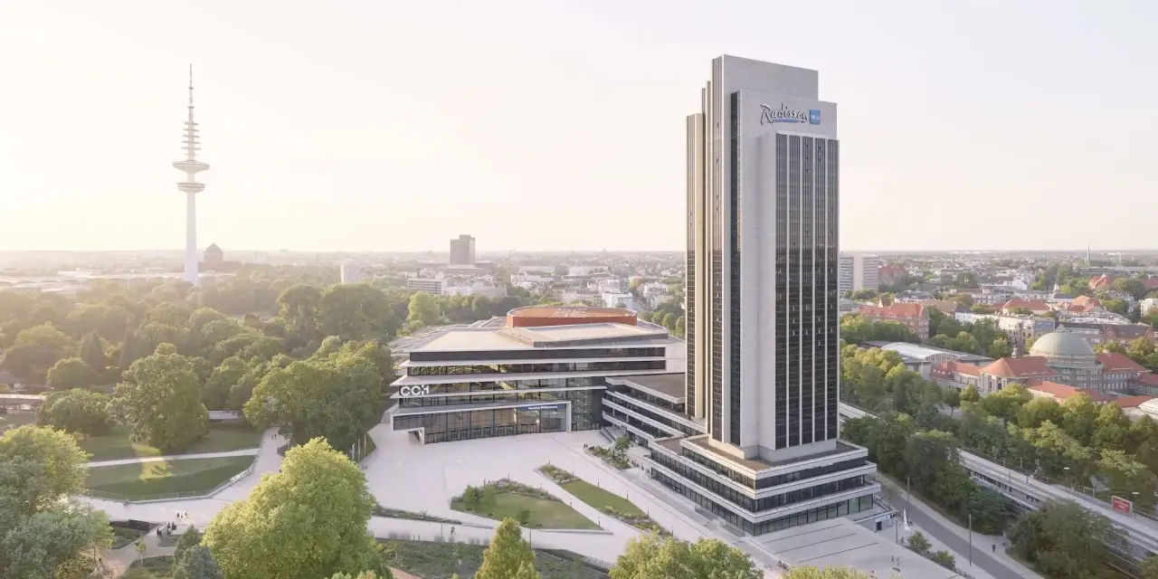 Radisson Blu Hotel w Hamburgu, z wieżą telewizyjną w tle, otoczony zielenią.