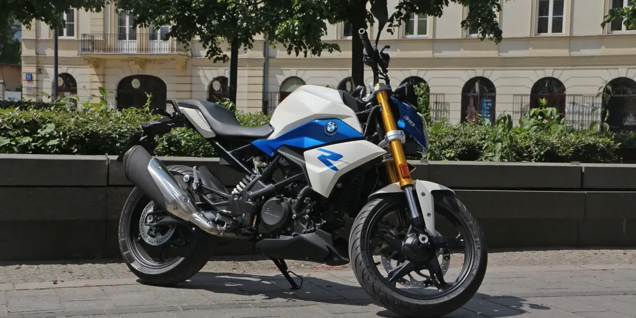Biało-niebieski motocykl BMW G 310 R na tle kamienicy. Sprawdź jego dane techniczne!