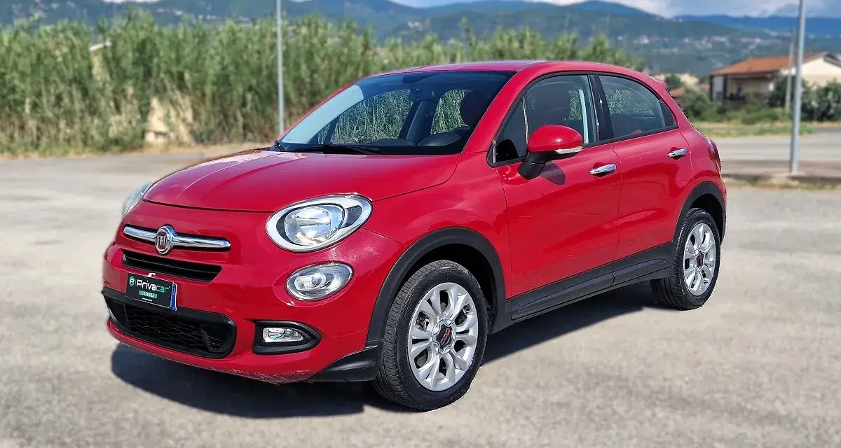 Fiat 500X rossa parcheggiata all'aperto, con montagne sullo sfondo. La pressione gomme è ottimale per ogni viaggio.