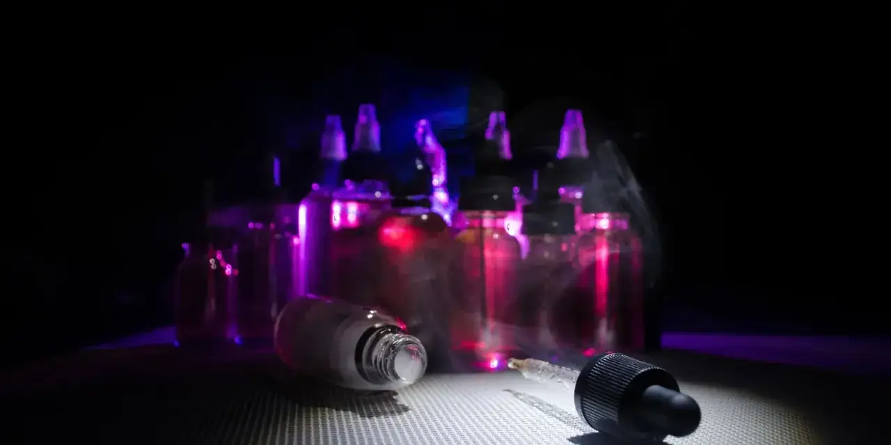 Gotas de nicokit como usar: frascos de líquido para vapear con luz púrpura y vapor.