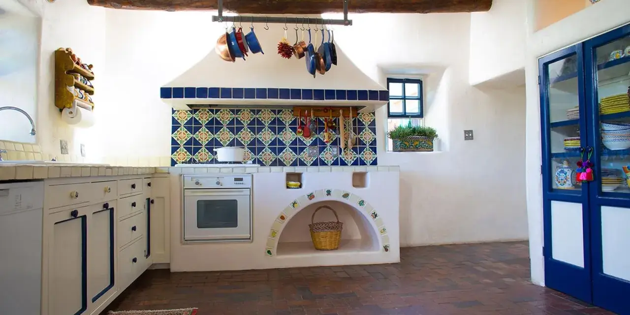 Cocina rústica con azulejos coloridos y detalles DIY, ideal para decorar casa de campo con poco dinero. Cestas y ollas cuelgan, creando un ambiente acogedor.