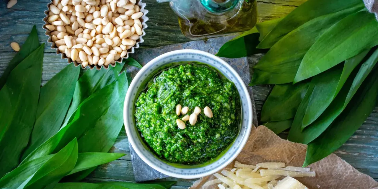 Pesto z czosnku niedźwiedziego, orzechów pinii i oliwy. Obok kawałek sera, który może być alternatywą, jaki ser do pesto zamiast parmezanu?