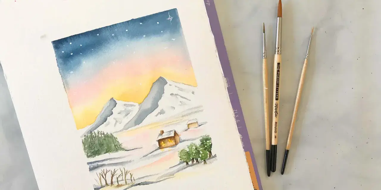 Une aquarelle montagne facile dépeint un paysage hivernal doux avec des montagnes enneigées, des chalets chaleureux et un ciel étoilé. Trois pinceaux sont posés à côté.