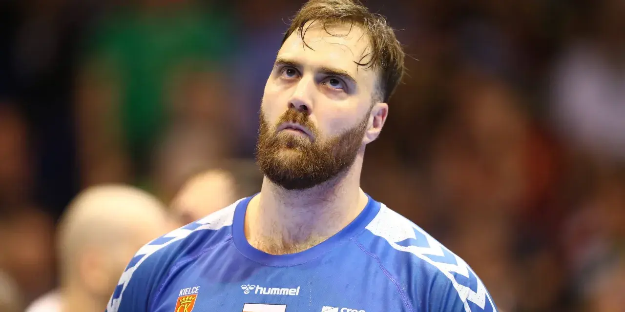 Andreas Wolf, zamyślony zawodnik w niebieskiej koszulce z herbem Kielc, patrzy w górę.